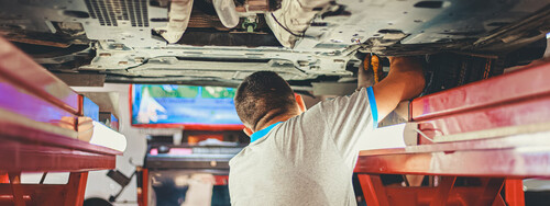 Ein Automechaniker prüft die Unterseite eines Autos.