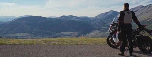 Ein Motorradfahrer schaut sich ein Bergpanorama an.